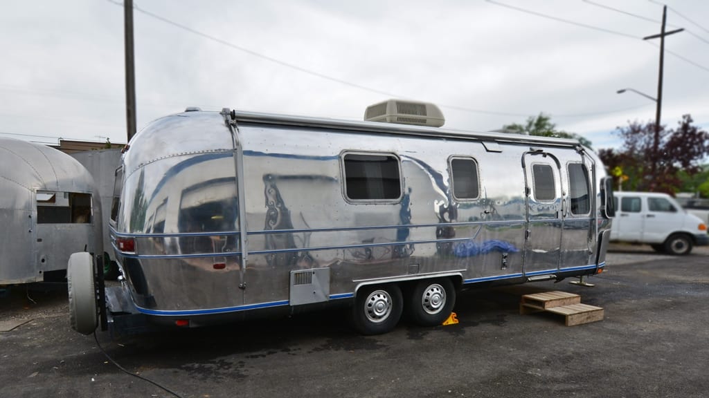 Polished aluminum exterior with rooftop AC unit, awning mount, and double-axle wheels on 1971 Airstream Sovereign