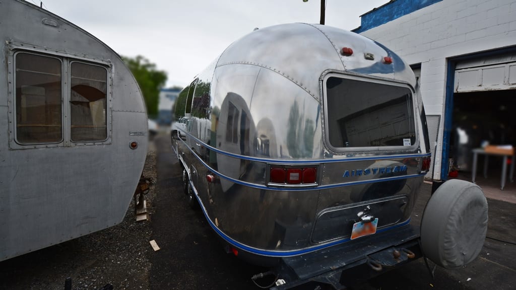 Polished rear exterior with blue trim, tinted window, spare tire mount, and taillights on 1971 Airstream Sovereign