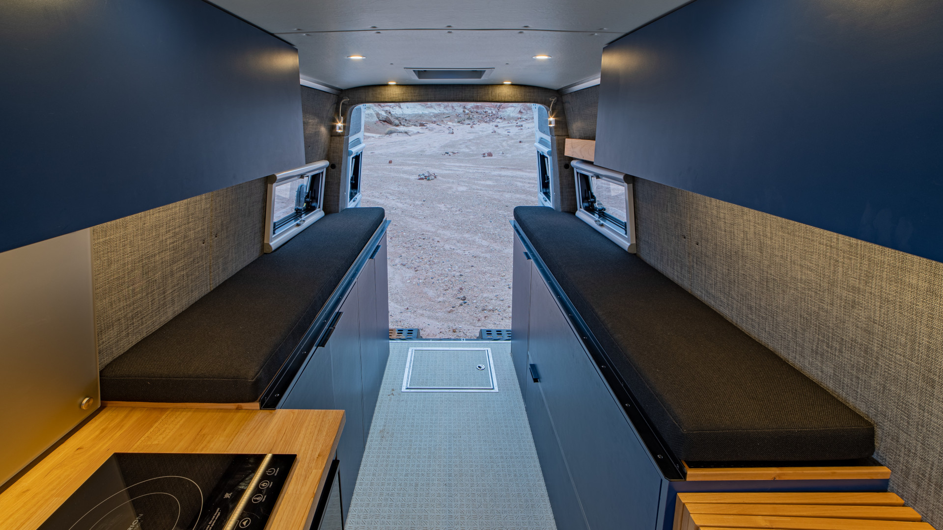 Twin bench beds with overhead storage, side windows, and induction cooktop in rear van interior layout, 2021 Sprinter 4x4 VS30