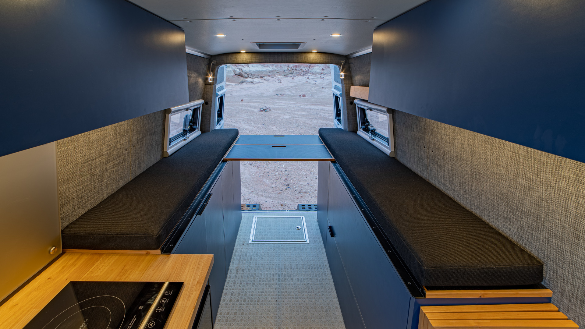 Fold-out bed platform between dual bench seats with under-seat storage and wall-mounted reading lights, 2021 Sprinter 4x4 VS30