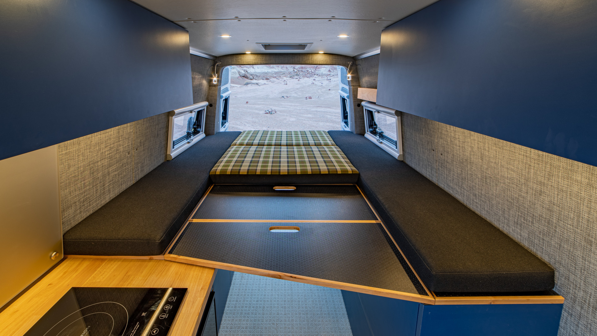 Fold-out bed platform with plaid cushion, under-bed storage drawers, and side bench seating in 2021 Sprinter 4x4 VS30