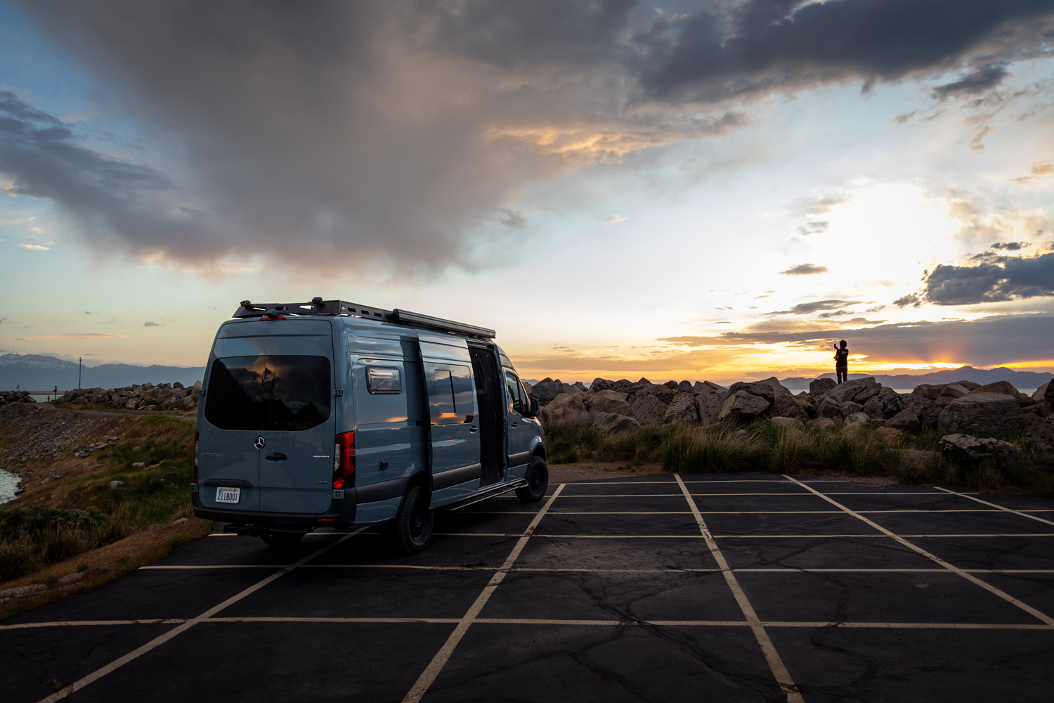 Rear view of custom high-roof Sprinter van with side windows, roof rack, and awning at sunset 2022 Sprinter 170