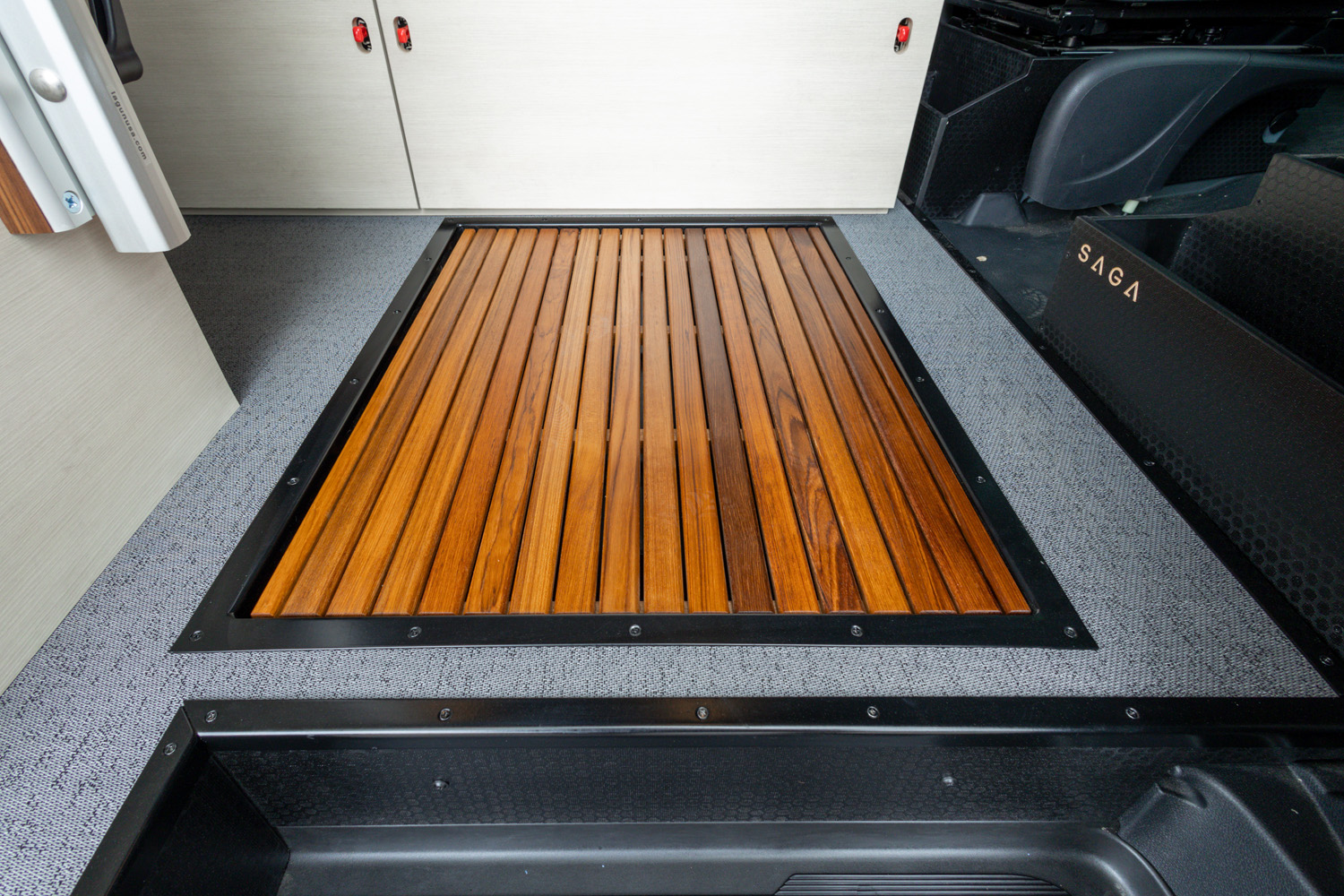 Teak slat inlay shower pan with black metal trim set into textured gray flooring and cabinetry panels, 2022 Sprinter 170 SAGA